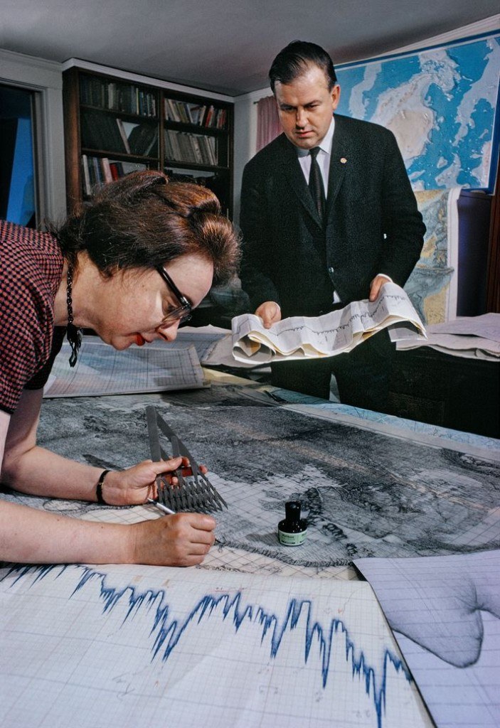 Marie Tharp at a drafting table with dividers; Bruce Heezen standing behind with a sounding profile.